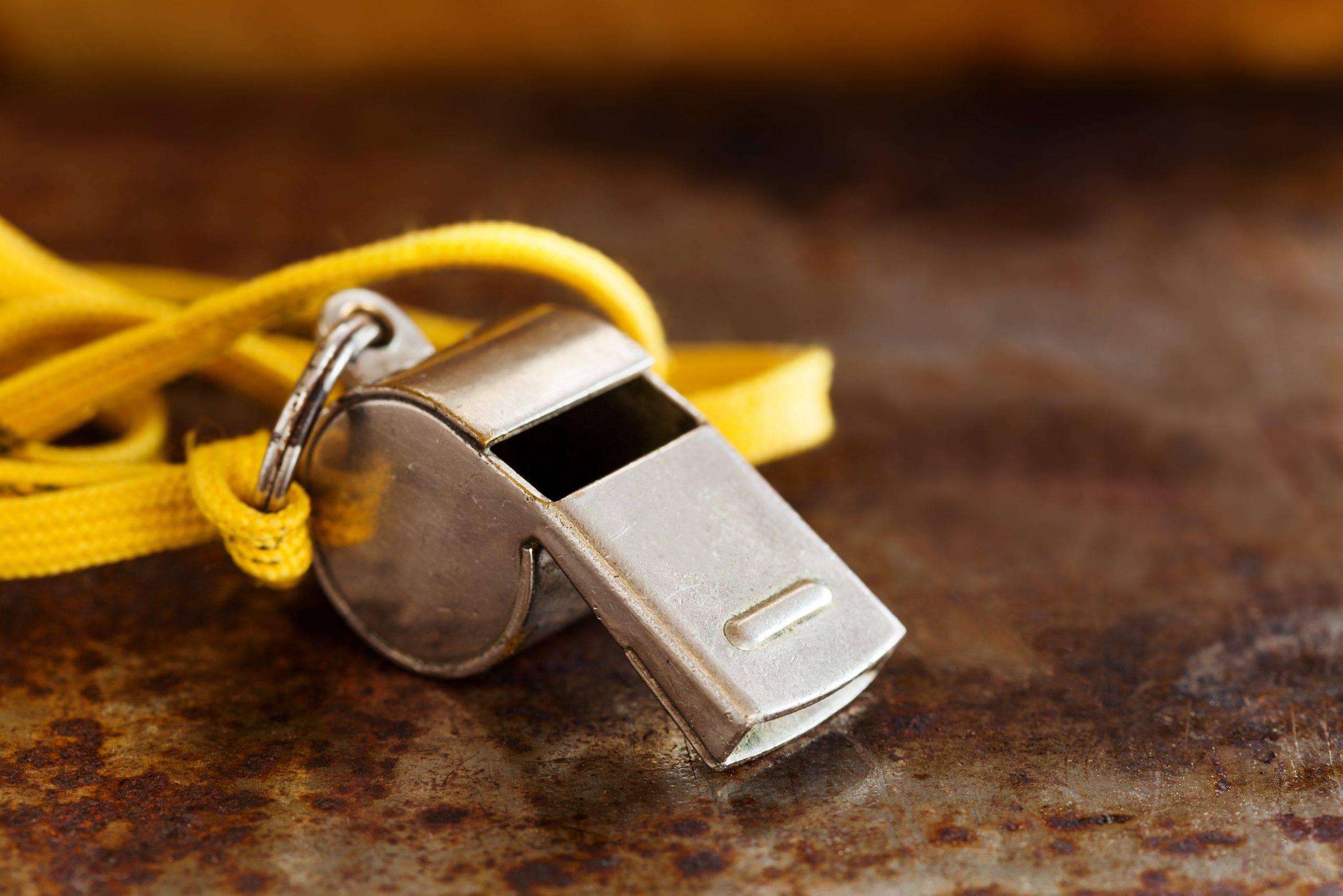 Vintage silver whistle on rusty metallic background. Referee trainer sport competition tool instrument, start finish stopping game and attention moments equipment. Close-up photo.
